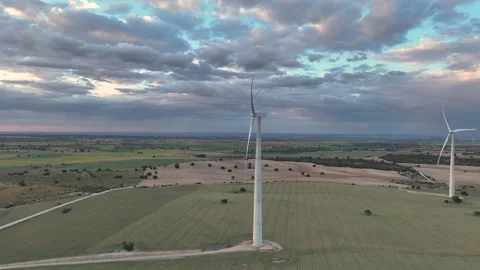 Side view of a windmill with its blades turning with a cloudy sky at sunset Stock Footage 274528016