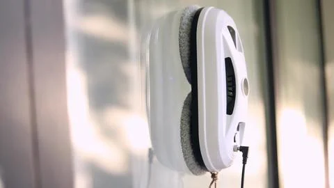 Side view of window cleaning robot attached to glass. Stock Photos