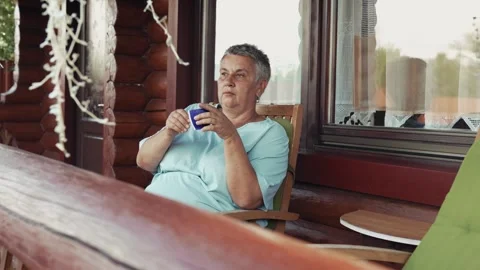 Side view of woman drinking water on outdoor cottage terrace Stock Footage 343385382