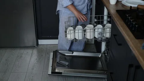 Side view of woman loading dishwasher with dirty plates, bowls, cutlery 库存影片 328996150
