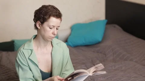 Side view of a woman reading in bed with a visible chest port, illustrating.. Stock Footage 335632435