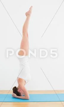Side view of a woman standing upside down on exercise mat Stock Photos