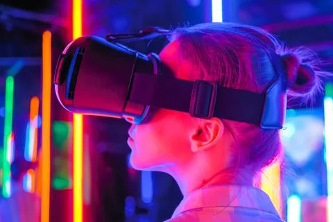Side view: woman using virtual reality headset at interactive VR exhibition Foto stock