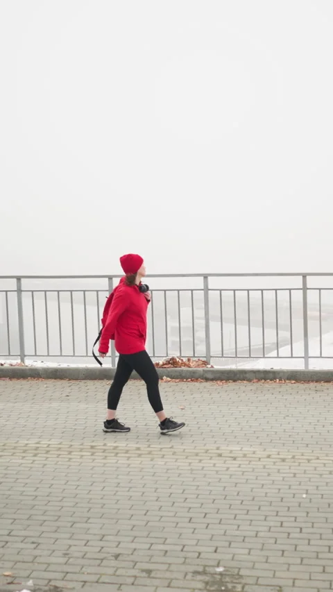Side view woman walking on patterned pathway near iron railing in fog Stock Footage 316593204