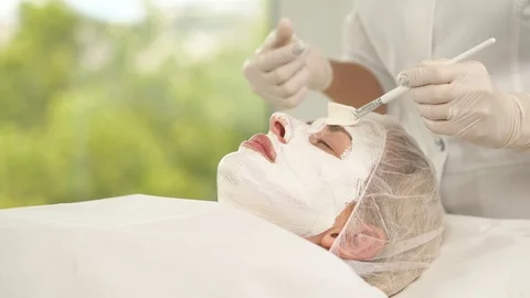 A side view of a woman's face covered with white mask. A hand with a brush Stock Footage 96188650