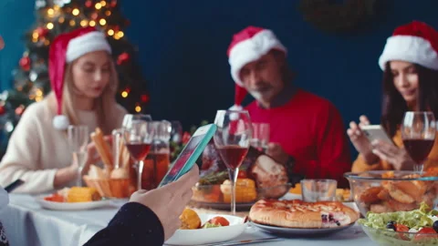 Side view of a woman's hand with a phone at a family dinner, where everyone is Stock Footage 144979888