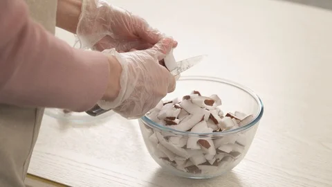 A side view of a woman's hands holding a coconut and cutting it to make a Stock Footage 106205162