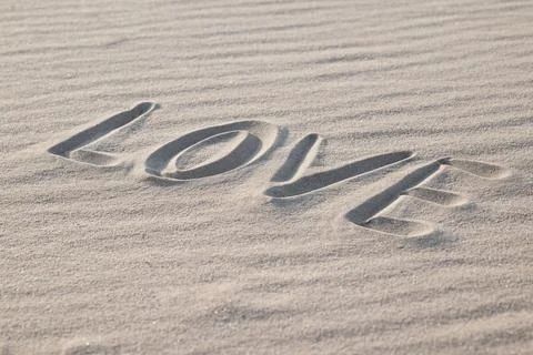 Side view on a word "love" written on the wavy sand, close up Stock Photos