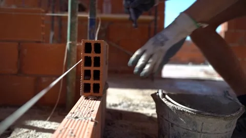 Side view of a worker raising a brick wall in the construction of a house. .. Video stock 242005160