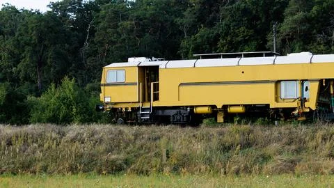 A side view of a yellow railway maintenance train on tracks with dry wild g.. Stock Photos