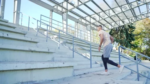 Side view. Young adult athlete of mixed race running up the stairs doing a work Stock Footage 234878747