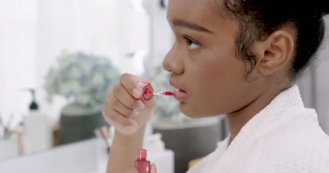Side view of young african american female gently applying lip gloss with soft Stock Footage 310313640