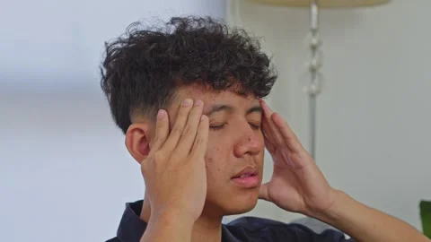Side view of young Asian man squeezing temples in intense pain suffering from Stock Footage 335484065