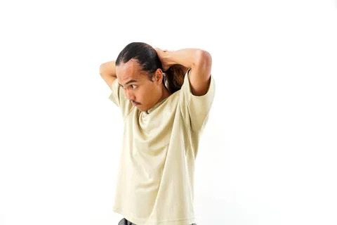 A side view of a young Asian man with long hair, wearing a beige t-shirt, t.. 스톡 사진