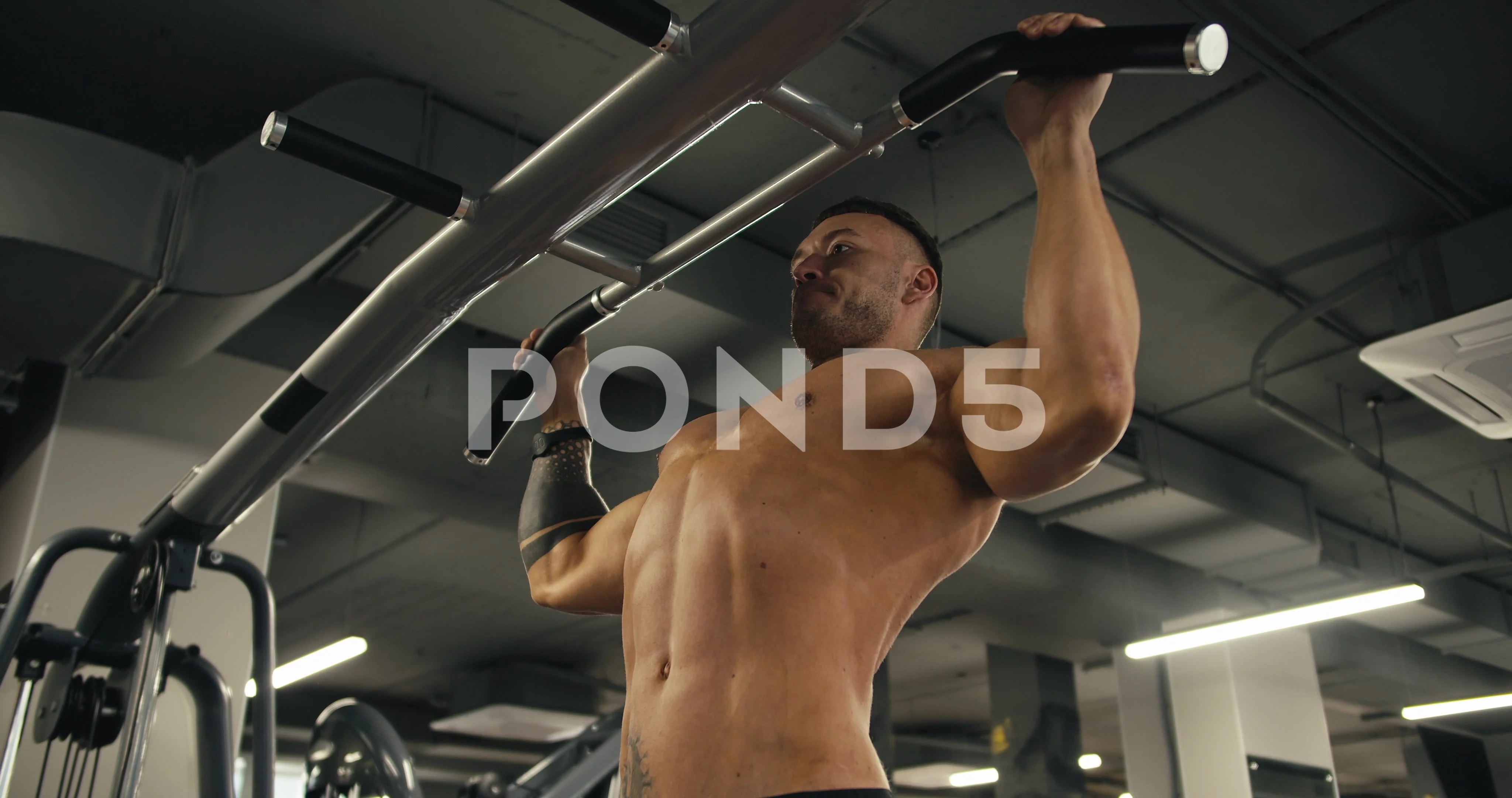 Side view of a young athlete with a naked torso who performs pull-ups while  in