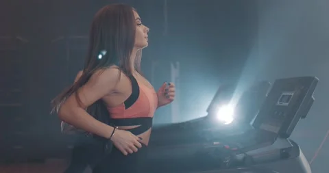 Side view of young attractive pretty woman in sportswear running on treadmill at Stock Footage 149483016