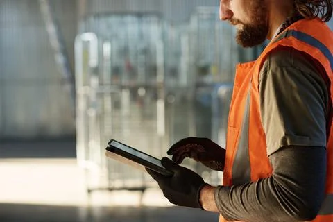 Side view of young bearded engineer in protective gloves and vest Stock Photos