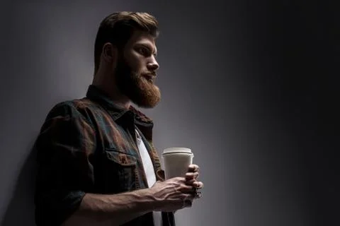 Side view of young bearded man drinking morning coffee Stock Photos