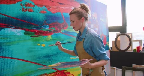 Side view of young beautiful happy Caucasian talented female painter drawing in Stock Footage 149572750