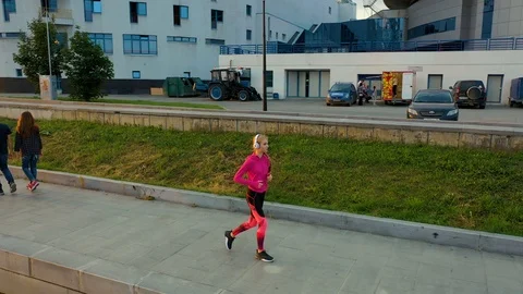 Side view of young blonde in white headphones woman running along pond Stock Footage 115084994