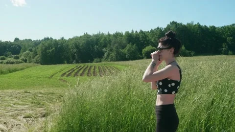 Side view of young brunnette in a green field talking on phone. Stock Footage 134043540
