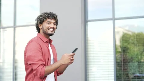Side view of young businessman looking at mobile phone walking in street  Stock Footage 302472911