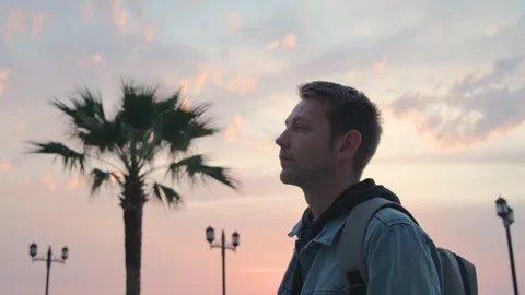 Side view of young Caucasian handsome man backpacker at sunset by the sea coast Stock Footage 243519490