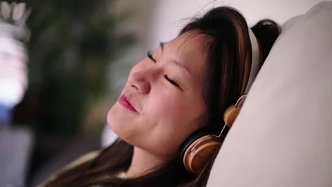 Side view of young cheerful Asian girl sitting in living room sofa shakes happy Stock Footage 255861853