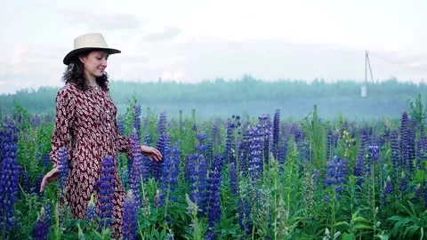 Side view. Young curly-haired caucasian girl in long light dress and straw hat Stock Footage 137749692