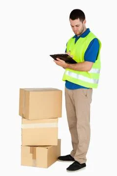 Side view of young delivery man filling in delivery note Stock Photos