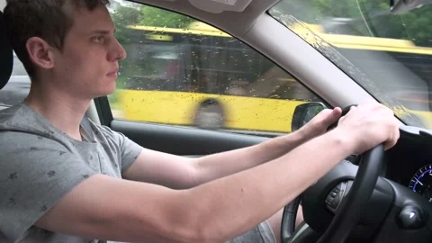 Side view of a young focused man driving a car in rainy weather 動画素材 134819557