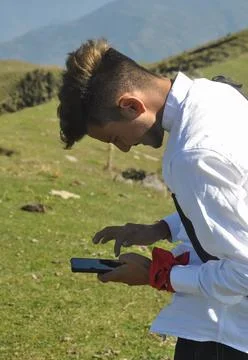 Side view of a young guy using his phone in the mountain  Foto stock