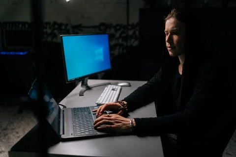 Side view of young hacker man wearing hooded stealing information, preparing to Stock Photos