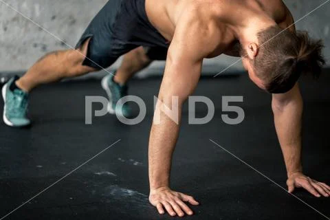 Side view of young handsome man in sportswear doing push-up at gym Stock Photos