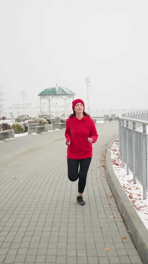 Side view young lady in red sweater running beside iron railing on patterned Stock Footage 316594288
