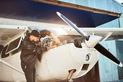 Side view of young male engineer inspecting small propeller airplane Stock Photos