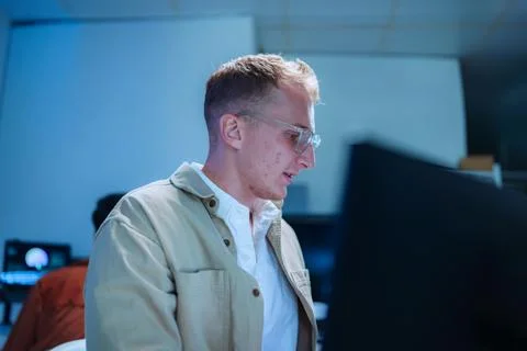 Side view of young male programmer looking at computer monitor analyzing sy.. Stock Photos