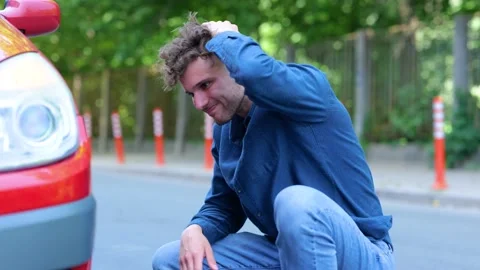 Side view of young male standing near his car looking at tire feeling sad. Close Stock Footage 203976582