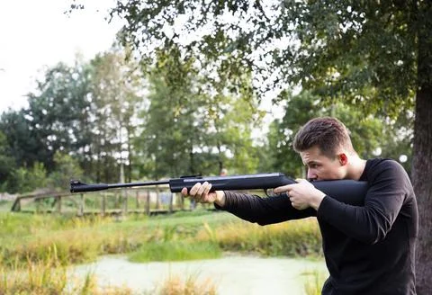 Side view of young man aiming rifle Stock Photos