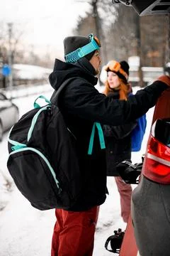 Side view of young man with backpack on his shoulder standing near car Stock-Fotos