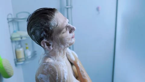 Side view of a young man cleaning his neck with soap foam in the home shower. Stock Footage 345531222