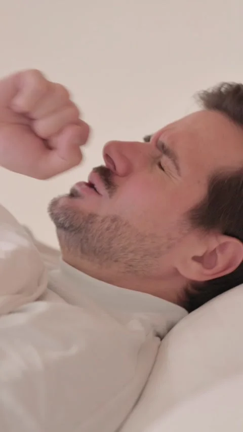 Side View of Young Man Coughing in Bed, vertical video Stock Footage 328565007