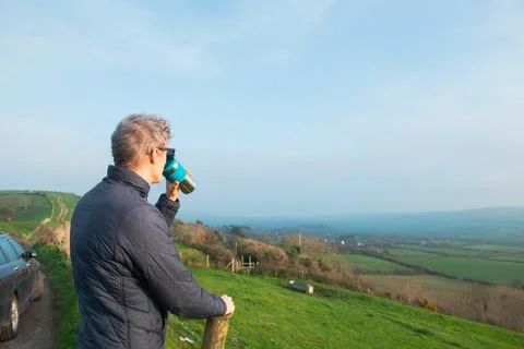 Side view young man drinking hot tea or coffee from thermos cup and enjoying Stock Photos