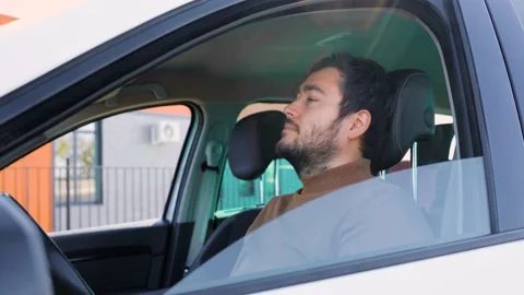 Side view young man driver sitting at wheel stopped to rest wearily resting his Stock Footage 221761979