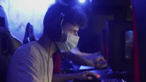 Side view of Young man in face mask plays in Online Video Game in Modern Stock Footage 136745321