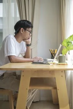 Side view of young man freelancer using computer laptop while sitting in comf Stock Photos
