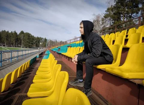 Side view of young man guy resting empty stadium seats Stock Photos