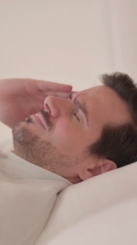 Side View of Young Man with Headache in Bed, vertical video Stock Footage 328565029