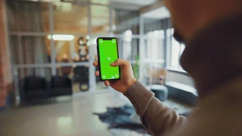Side view young man holding a smartphone touching green screen chroma key mock Stock Footage 128247039