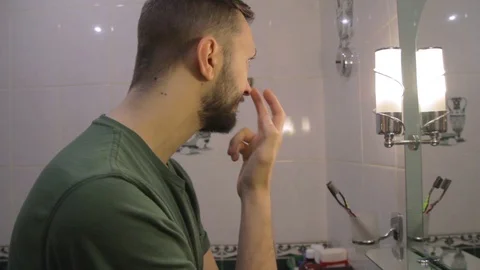 Side view on young man looking at the mirror, checking face for skin diseases Stockbeeldmateriaal 104022010